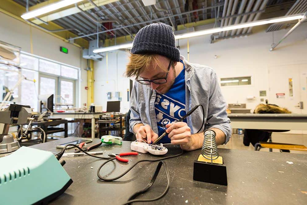 Student soldering electronics as part of tuition free program at University of 罗彻斯特